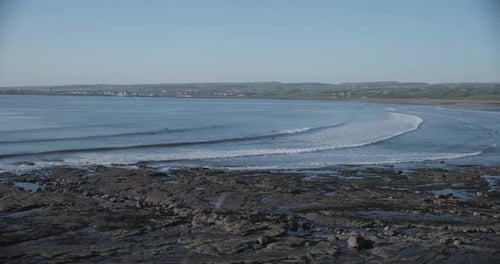 Strip of Irish coastline with waves coming in in beautiful patterns. Rocky / sandy shore of Ireland
