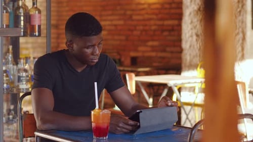 technology, tablet - black guy at the restaurant reads emails on the tablet
