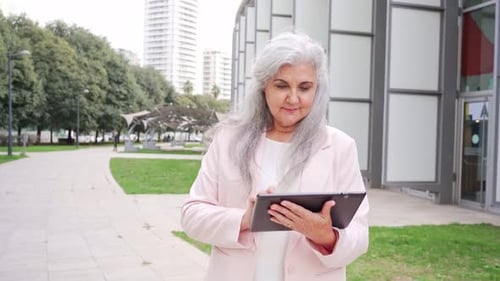 Smiling Woman Using Tablet Device Outside Building
