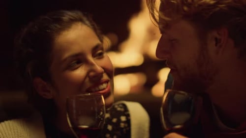 Romantic young couple smiling by cozy fireplace