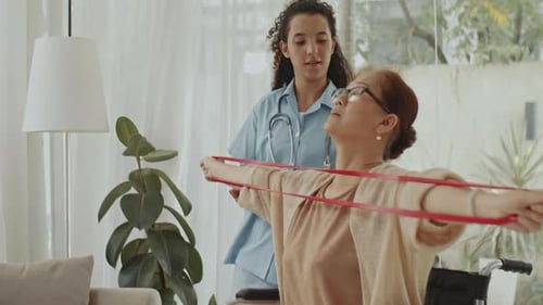 Healthcare Worker Assists Senior Woman with Resistance Band Exercises