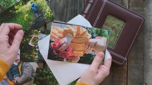 Persona mira fotos impresas para un álbum de fotos familiar desde arriba