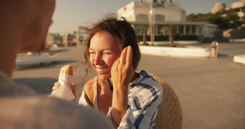 Woman Enjoys Snack with Friend in Sunny Setting