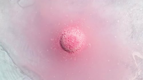Pink Bath Bomb Dissolving in Water Overhead