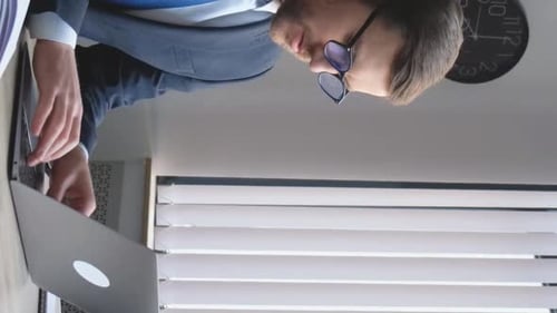Confident Businessman Sitting at the Office Table and Working with a Laptop He is Typing