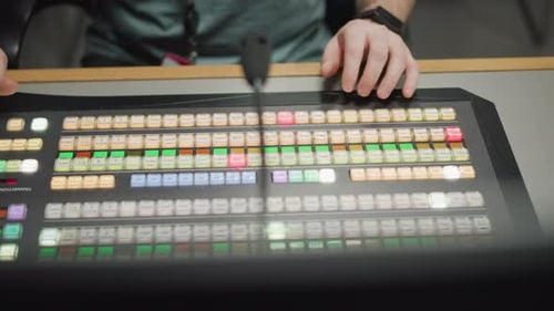 Hands Operating Video Switcher in Control Room with Broadcast Equipment