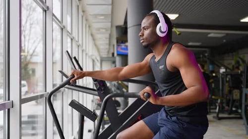 Fitness Male Using Air Bike for Cardio Workout at Training Gym