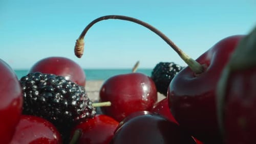 Berries of cherries, mulberries and strawberries against the backdrop of the sea, beach. Dolly slide