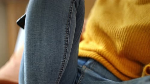 Unrecognizable Woman Sitting On A Couch With A Cellphone. Close-up Shot