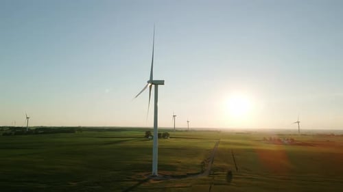 Wide Aerial Drone View of a Wind Farm Park with Wind Turbines Standing in a Wheat Field at Sunset