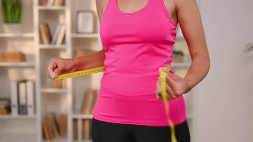 Adult Measures Waistline with Tape Measure Indoors