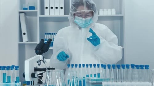 Scientist Works With Microscope and Test Tubes