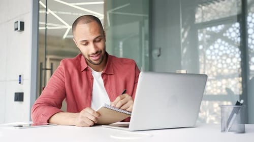 Man Attends Meeting with Laptop and Notepad