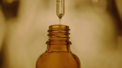 Close-up Pipette Dropping Liquid Into Amber Bottle