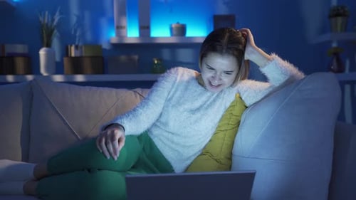 Woman Laughing, Relaxing on Couch Watching Laptop at Night