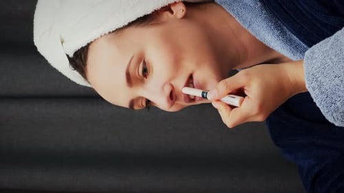 Woman applying lipstick on lips and looking at mirror.