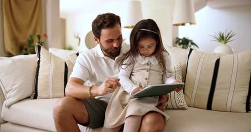Father and Daughter Looking at Tablet Together on Couch