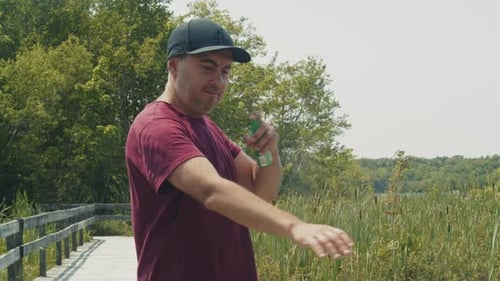 Man spraying mosquito repellent on arm outside