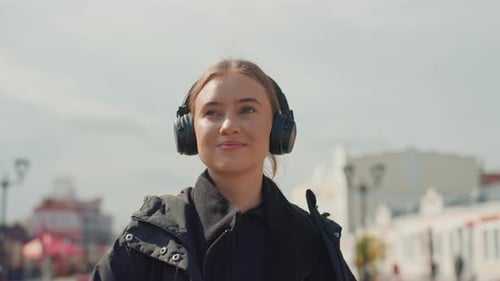 Woman with Headphones Drinking Coffee on City Street