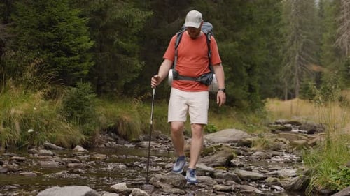 Male Hiker Crossing Creek in Forest