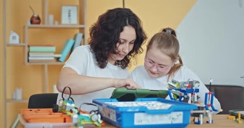 Une enseignante et une jeune étudiante apprennent les bases techniques de la programmation de robots Une enseignante