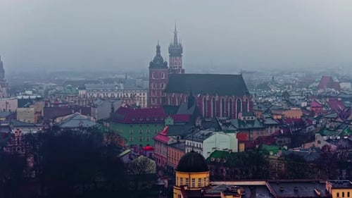 Misty Krakow skyline with St Mary’s Basilica rising above colorful Old Town rooftops on an overcast