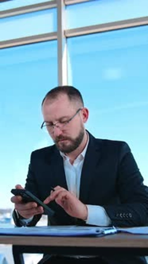 Man Using Phone at Desk in Modern Office