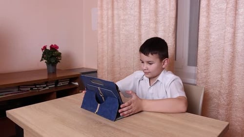 Young Boy Using Tablet Device at Wooden Table
