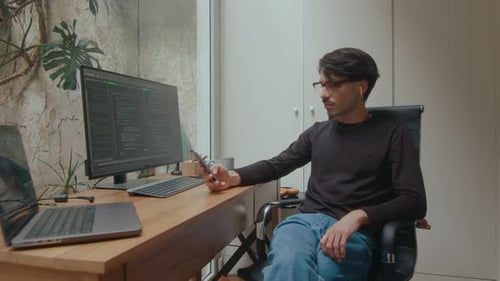 Computer Programmer Using Phone in Home Office