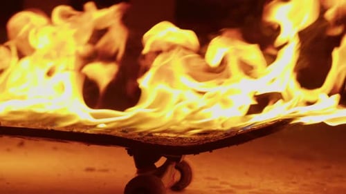 Flaming Skateboard Resting on the Ground at Night