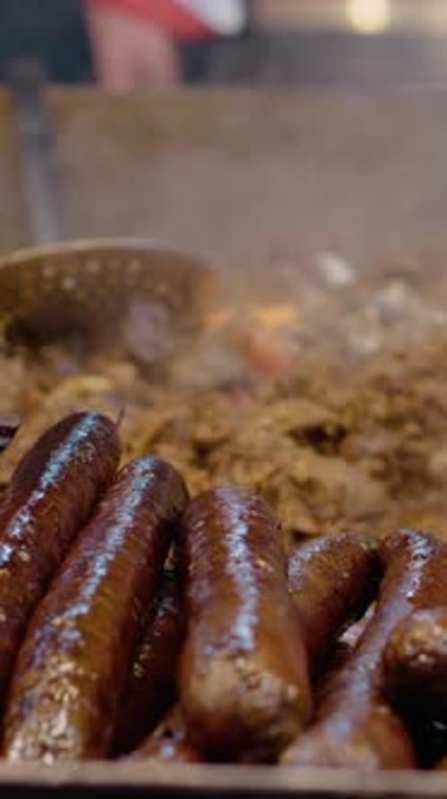 Vertical video Street food vendor preparing sausages on a hot plate