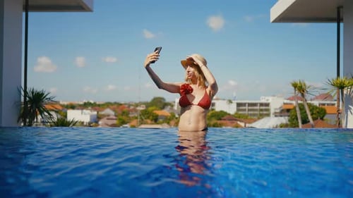 Female Travel Blogger Filming Herself By Mobile Phone in Beautiful Swimming Pool Portrait of