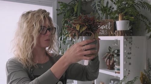Gorgeous blonde botanist admiring the her newly potted plant