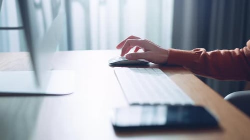 Close-up of a woman hand using white wireless mouse on a work desk