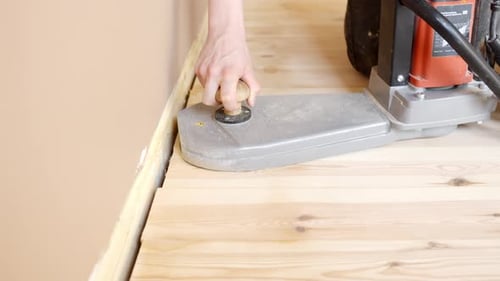 Sanding wooden floor edges using a hand-held tool for a smooth and polished finish