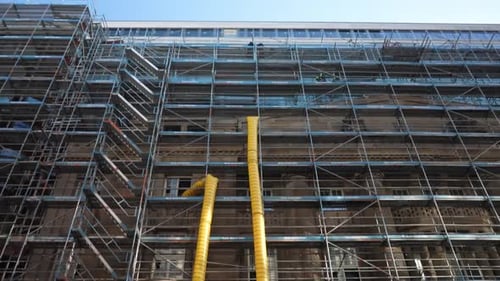 Fachada do edifício histórico coberta com andaimes durante a renovação, trabalhos de restauração exterior e