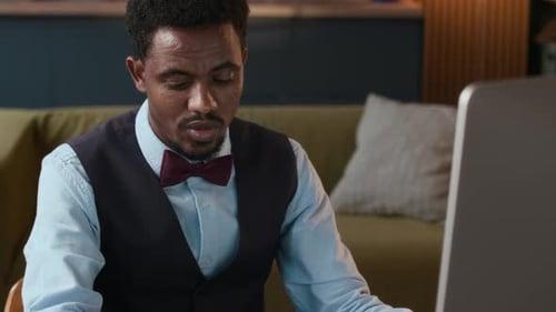 Man in Bow Tie Works on Computer at Home