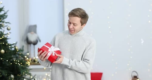 Man Holding Christmas Present in Living Room Indoors