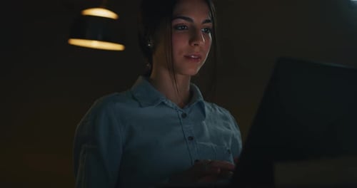 Slow motion of a young beautiful business woman is working with a computer in the evening in a off