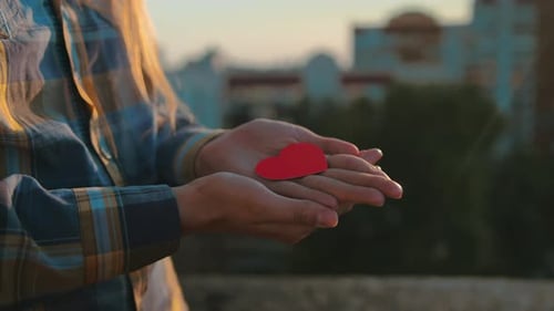 Holding a Red Heart in Palms at Sunset