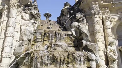 A Fountain in Front of a Building with Statues on It