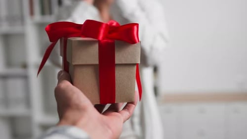 Person Giving Gift Box to Another Person Indoors