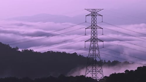 A high voltage tower and a sea of raging, tumbling clouds on a summer morning.