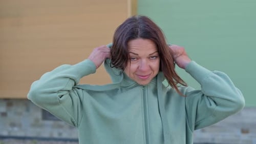 Smiling Woman Adjusts the Hood on her Sweatshirt