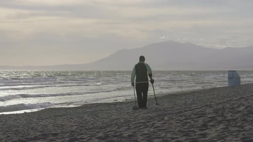 Young man using metal detector a the beach