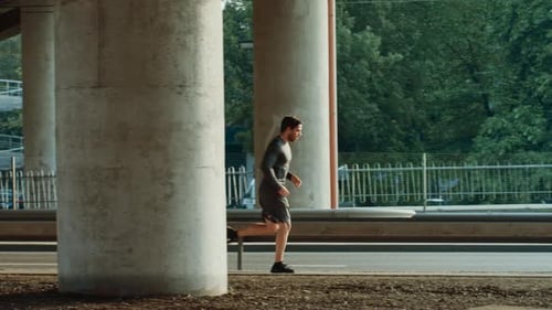 Athletic Young Man in Sports Outfit is Jogging in the Street. He is Running in an Urban Environment
