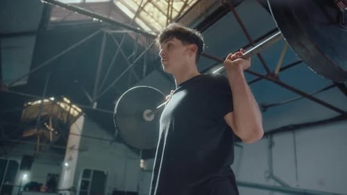 Young Sportsman Doing Squats with Barbell during Gym Workout