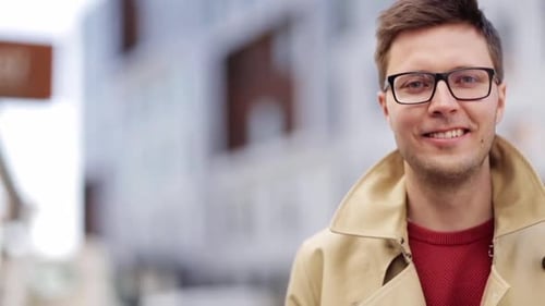 Smiling man in eyeglasses expressing joy outdoors in the city