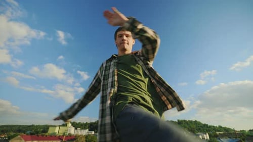 Junger Tänzer spielt Hip Hop draußen auf dem Dach Brünetter Mann genießt Tanz und schaut in die Kamera
