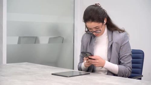Young Woman Using Stylus and Smartphone in Office